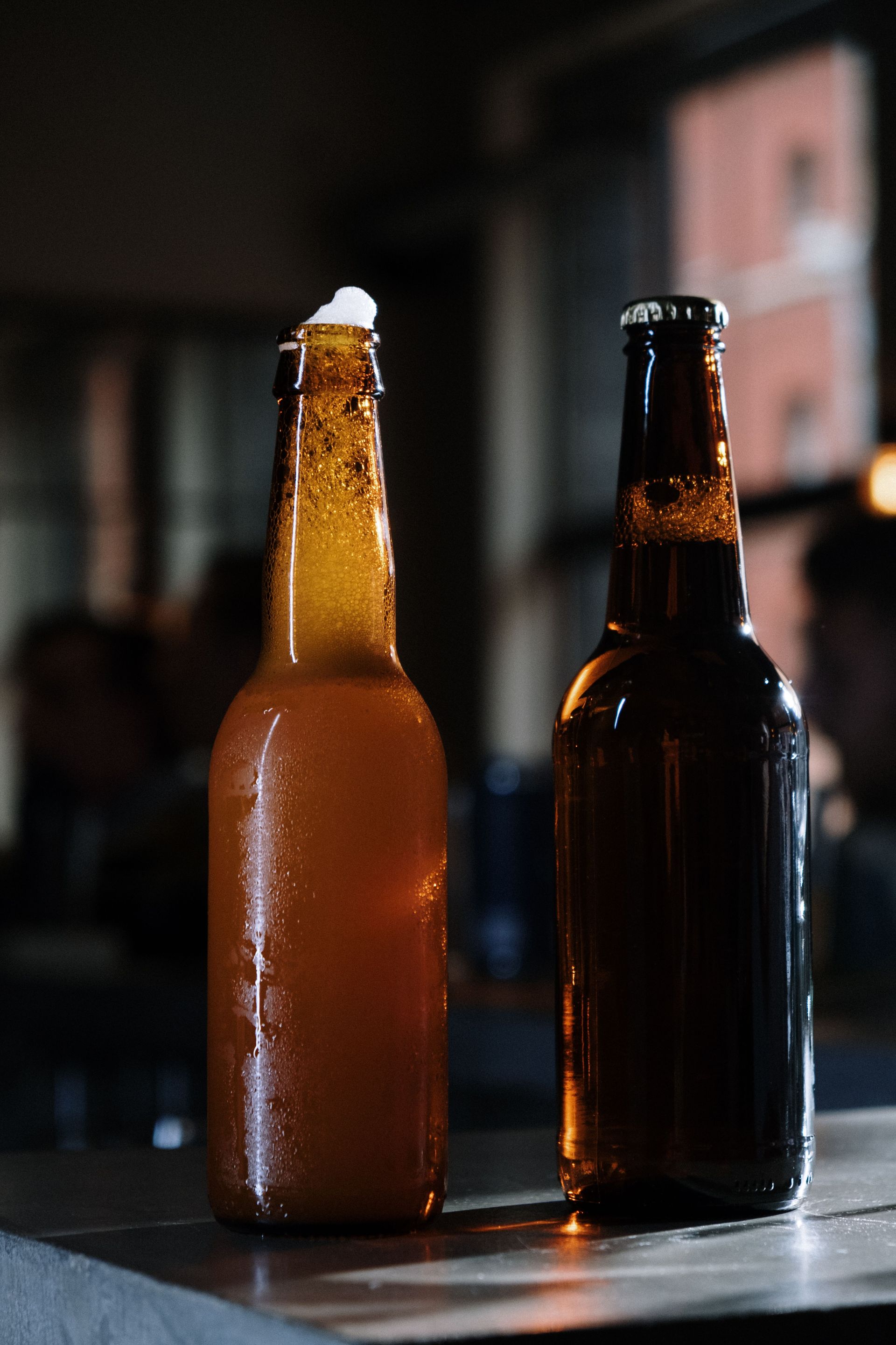 Two beer bottles on a table with soft bokeh, perfect for beverage themes.
